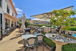 d'une terrasse avec des tables, des chaises et un arbre. dans l'établissement Hotel & Restaurant Perla Riviera, à Villeneuve-Loubet