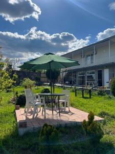 einen Tisch, zwei Stühle und einen grünen Regenschirm in der Unterkunft Hotel Classic in Telawi