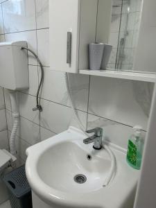 a white bathroom with a sink and a mirror at Kršić Apartman in Baošići