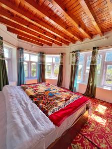 ein Schlafzimmer mit einem großen Bett in einem Zimmer mit Fenstern in der Unterkunft Kolahoi Heights Guest House in Pahalgām