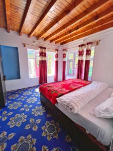 a bedroom with a bed with red curtains and blue carpet at Kolahoi Heights Guest House in Pahalgām
