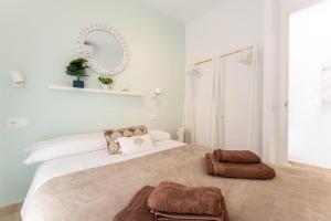een witte slaapkamer met een groot bed en een spiegel bij MalagaSuite Sun & Sea Fuengirola in San Francisco