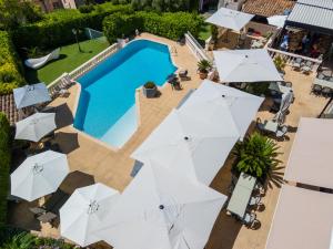 uma vista sobre uma piscina com guarda-sóis brancos em Hotel & Restaurant Perla Riviera em Villeneuve-Loubet