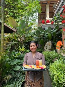 una mujer está sosteniendo una bandeja de comida en Tanah Semujan Ubud en Ubud