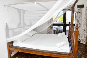 a bedroom with a canopy bed with white sheets at Mavericks Convenient Cozy Loft in Diani's CBD in Ukunda