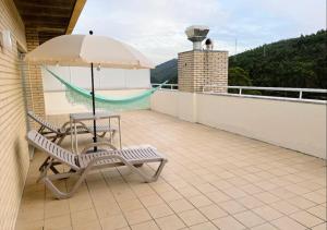 a chair and an umbrella on a balcony at Espaçoso T3 com terraço & churrasqueira in Campo