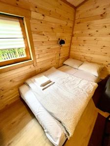 Cama pequeña en habitación de madera con ventana en Domek drewniany, en Podzamcze