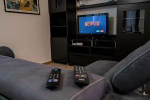 dois controlos remotos sentados num sofá em frente a uma televisão em Casa Spezia - Metro Vicina, Wi-Fi Rapido & Netflix em Turim