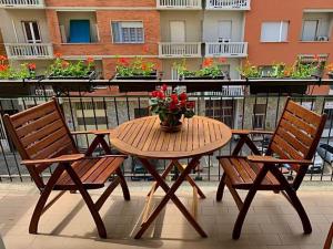 uma mesa e cadeiras de madeira com um vaso de flores numa varanda em Casa Spezia - Metro Vicina, Wi-Fi Rapido & Netflix em Turim