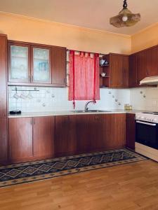 a kitchen with wooden cabinets and a red curtain at Batsi Bay View Maisonette in Andros