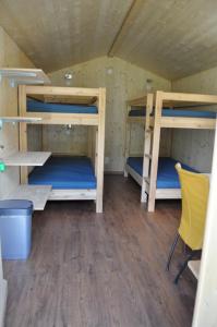 Camping Sur En في سنت: غرفة بها ثلاثة أسرة بطابقين وكرسي أصفر