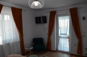 Agropensiune Caban في جوريلوفكا: غرفة معيشة مع ستائر برتقالية وكرسي أخضر