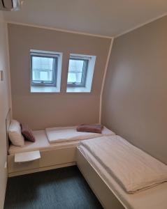 2 Betten in einem kleinen Zimmer mit 2 Fenstern in der Unterkunft Open-Water-Resort in Geierswalde