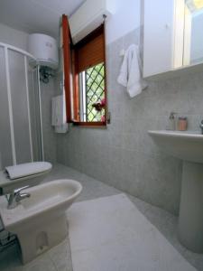 a bathroom with a sink and a toilet and a window at Villa Capinera in Lignano Sabbiadoro