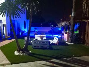 podwórko z kanapą i palmami w nocy w obiekcie GATU PREMIUM Villa Lurberri piscina privada, 4 dormitorios, 2 baños, parking , jardines, " Preferente mayores de 25 años y familias " ín y barbacoa w mieście Chiclana de la Frontera