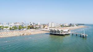 una playa con un muelle y un montón de gente en el agua en Villa Capinera en Lignano Sabbiadoro