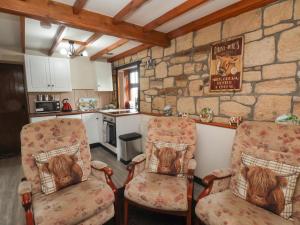 a kitchen with two chairs and a stone wall at Cow Byre Cottage in Whitby