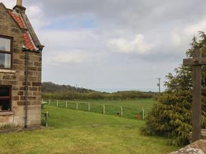 a field next to a house with a fence at Cow Byre Cottage in Whitby