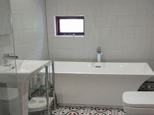 a bathroom with a tub and a toilet and a window at Sgurr Mor Lodge - Smmd in Balmacara