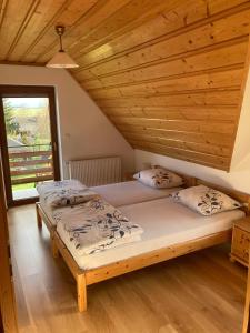 two beds in a room with a wooden ceiling at Domek Letniskowy in Zubrzyca Dolna