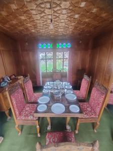 a dining room table with chairs and plates on it at Houseboat Young Manhattan in Srinagar