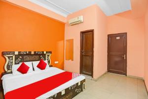 - une chambre avec des murs orange et un lit avec des oreillers rouges dans l'établissement Flagship Hotel Mirage, à New Delhi
