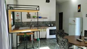 a kitchen with a sink and a table and a refrigerator at Casita de la montaña in Río Ceballos
