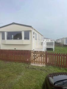 a white house with a fence in a yard at 185 Holiday Resort Unity in Berrow