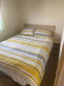 Berrow的住宿－185 Holiday Resort Unity，卧室内的一张床位,配有黄色和蓝色的毯子
