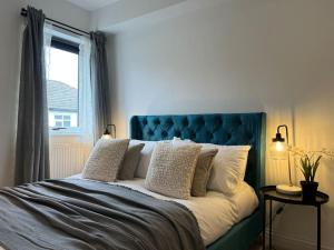 um quarto com uma cama azul com almofadas e uma janela em East Rd em Londres
