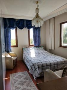 a bedroom with a bed with blue curtains and a chandelier at 1915 Çanakkale Köprü manzarali 700m2 bahceli mustakil ev in Canakkale