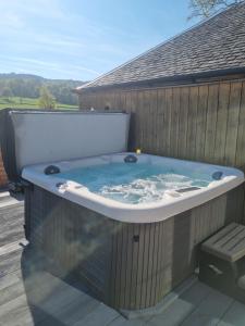 une baignoire jacuzzi sur la terrasse d'une maison dans l'établissement Auchendennan Farm Self Catering Cottages, à Balloch