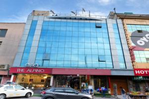 a large glass building with cars parked in front of it at The Alpino Hotel in New Delhi