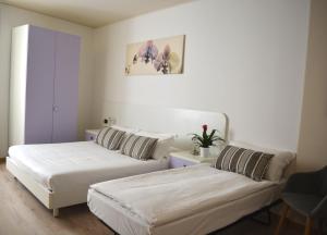 - 2 lits dans une petite chambre aux murs blancs dans l'établissement Alle Porte, à Riva del Garda
