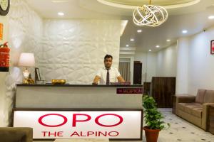 a man standing behind a counter in a lobby at The Alpino Hotel in New Delhi