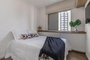 Habitación blanca con cama y ventana en Duplex Oscar Freire, en São Paulo