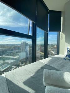1 dormitorio con ventana grande con vistas a la ciudad en Bright Urban Oasis, en Melbourne