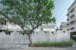 a white fence with a tree in front of a building at InJoy Snow Hotel in Ban Chuat Plai Mai