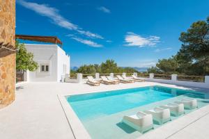 una piscina con sedie a sdraio e una villa di Villa Horizonte - Eivillas Ibiza a Port des Torrent
