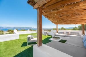 un patio esterno con mobili bianchi e erba di Villa Horizonte - Eivillas Ibiza a Port des Torrent