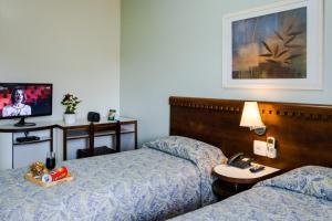 a hotel room with two beds and a television at Vitoria Regia Hotel Bauru in Bauru