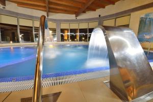 ein Schwimmbad mit Wasserrutsche in einem Gebäude in der Unterkunft Hotel Spa Norat Torre Do Deza 4* Superior in Lalín
