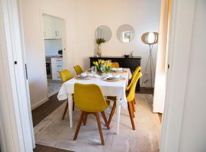 a dining room with a white table and yellow chairs at Tio Zé - Casas de Selim in Arcos de Valdevez