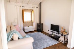 ein Wohnzimmer mit einem weißen Sofa und einem TV in der Unterkunft Tio Zé - Casas de Selim in Arcos de Valdevez