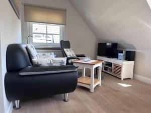 a living room with a couch and a table and a television at Schmucke-Huus-Appartement-2 in Westerland
