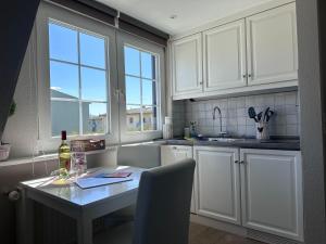 a kitchen with white cabinets and a table with a bottle of wine at Schmucke-Huus-Appartement-2 in Westerland