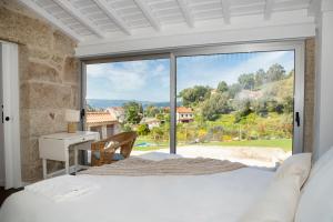 a bedroom with a bed and a large window at Altiva - Casas de Selim in Arcos de Valdevez
