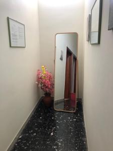 a mirror in a hallway with a vase with flowers at BnB Nonna Maria in Poggiomarino