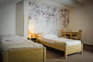 two beds in a room with a table and a painting at Willa Centrum in Supraśl