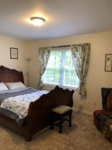een slaapkamer met een bed, een raam en een stoel bij heather house in Nokesville